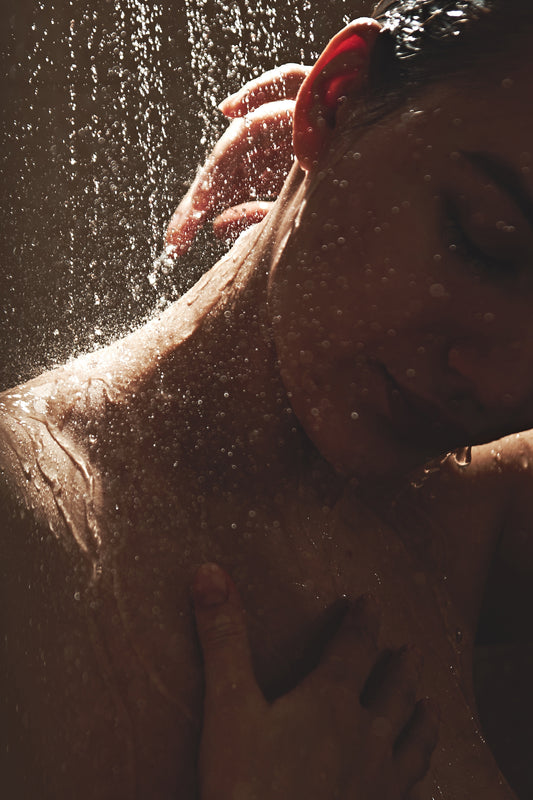 Close-up of a girl's neck and head under drops of water, low light